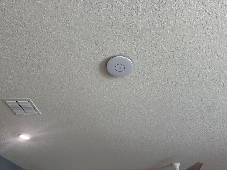 Wireless access point mounted on a textured ceiling.