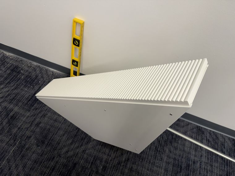 Equipment shelf during installation, with a spirit level resting against the wall.