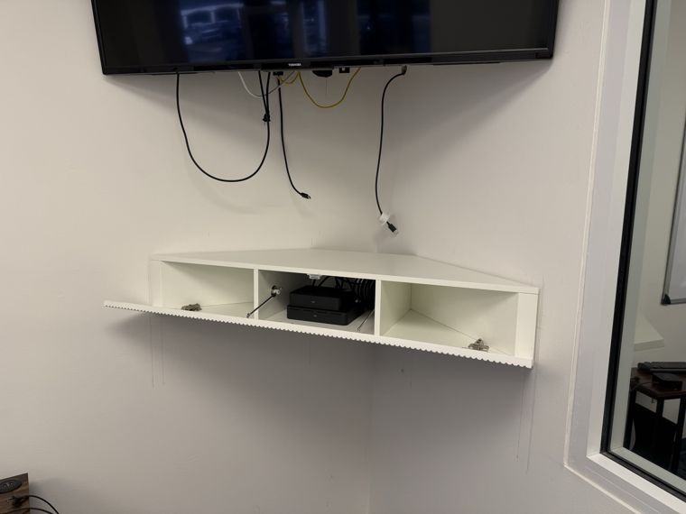 Wall-mounted display with an equipment shelf and connecting cables.