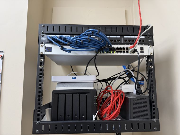 Network rack containing a switch, storage device and bundled patch cables.