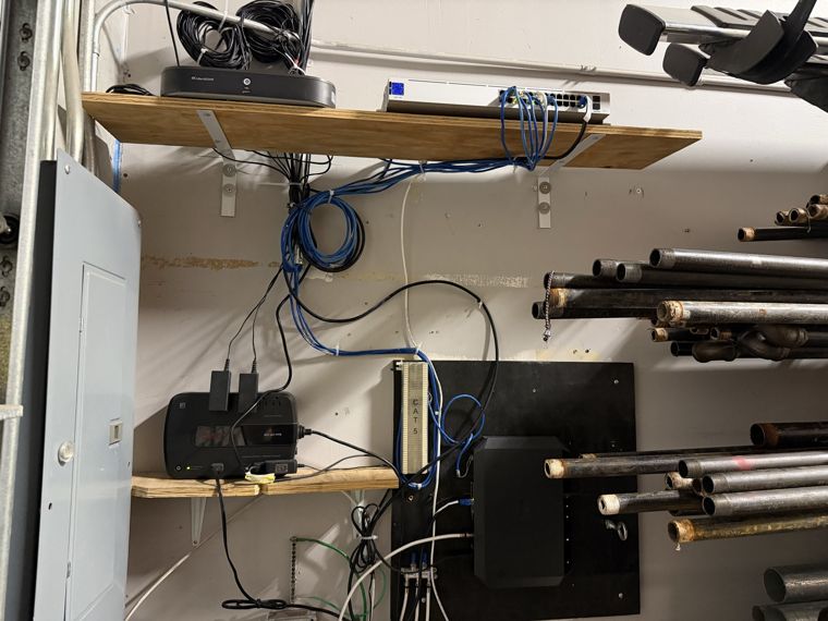 Networking equipment and cabling arranged on shelves in an equipment room.