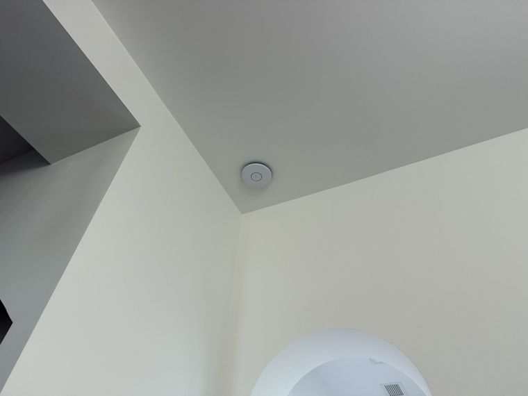 Wireless access point positioned near an interior ceiling corner.